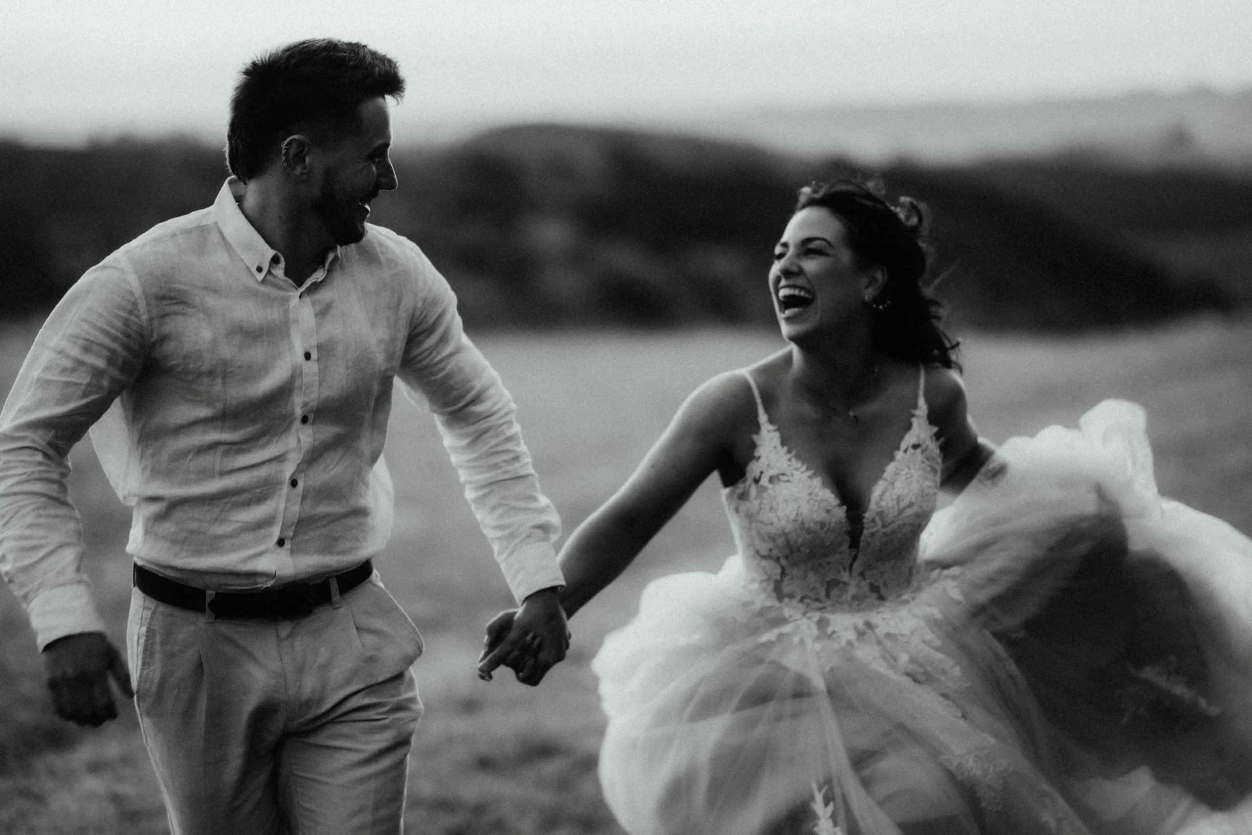 Black and white photo of a laughing bride and groom running together, Olivia Rose Bridal real bride